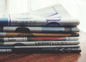 A stack of folded newspapers placed on a wooden table, symbolizing news and information.